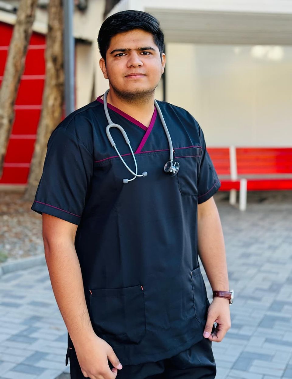 Dr. Muhammad Usman, in dark scrubs with a stethoscope around his neck, standing outdoors.